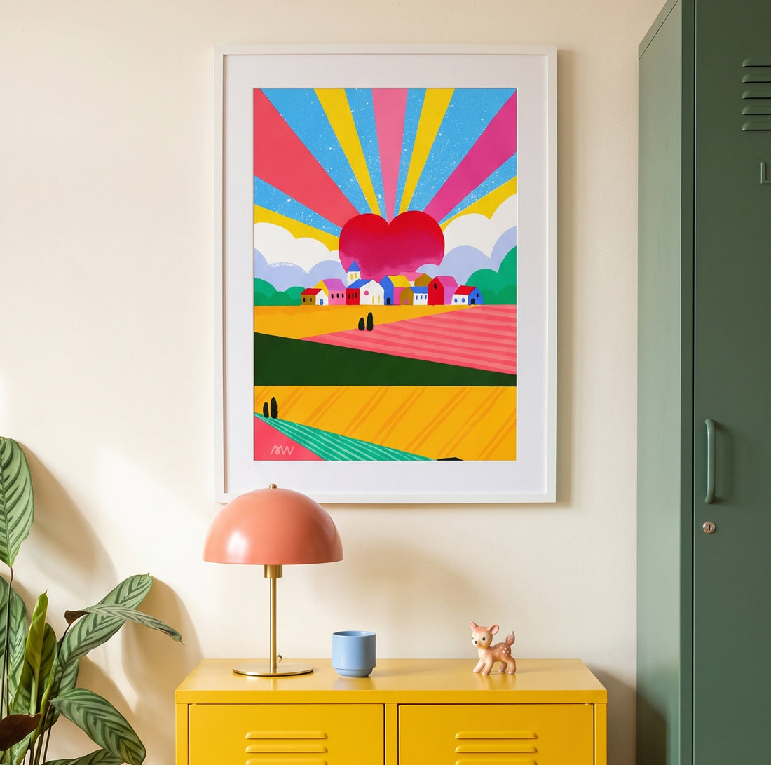 Tirage d'art Campagne mon amour encadré de blanc au-dessus d'un meuble jaune, entre une lampe rose et une plante verte