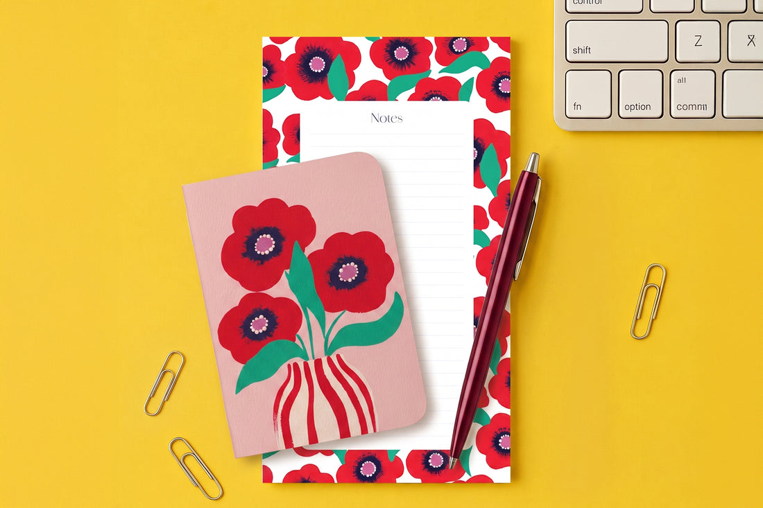 Pack Coquelicot posé sur un bureau jaune : bloc-notes à bordure fleurie et carnet de poche aux coquelicots