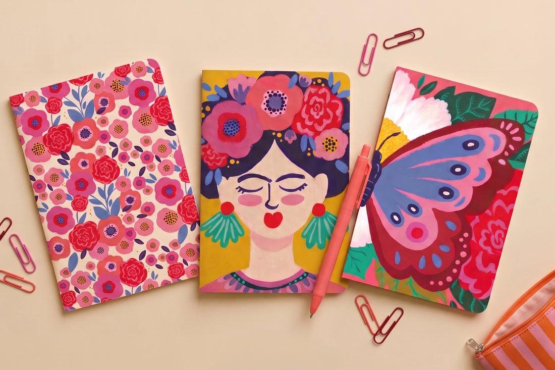 Pack 3 carnets A5 au choix présenté à plat : carnets floral, Frida et papillon avec crayons et trombones