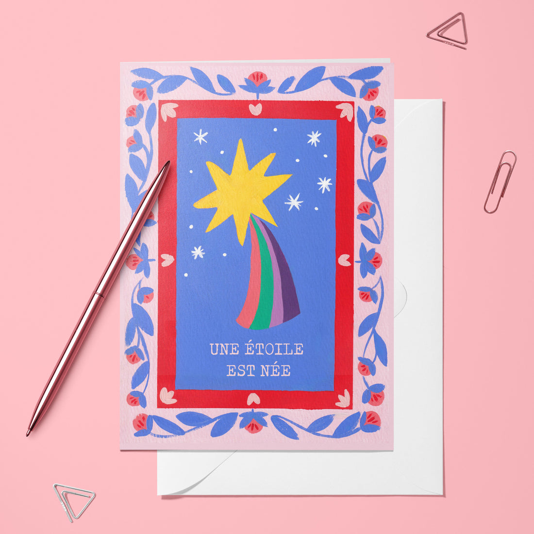 Carte pliée Une étoile est née posée avec un stylo doré et son enveloppe, étoile filante dans un cadre fleuri