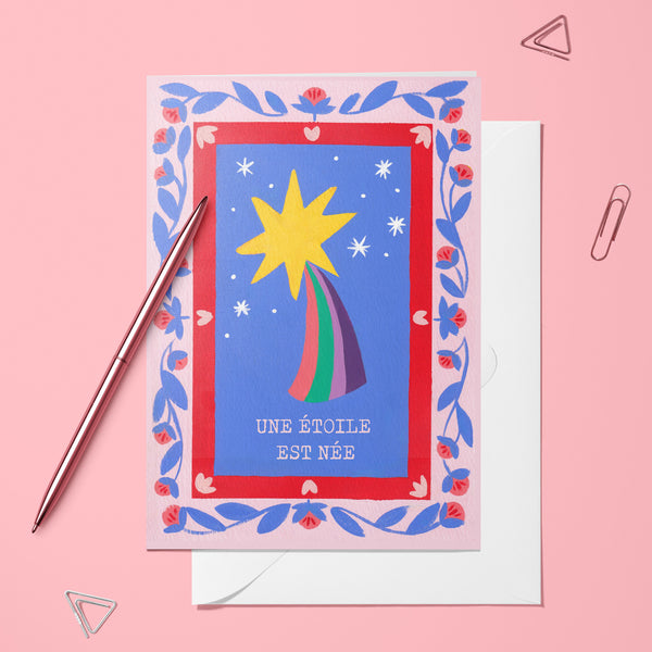 Carte pliée Une étoile est née posée avec un stylo doré et son enveloppe, étoile filante dans un cadre fleuri