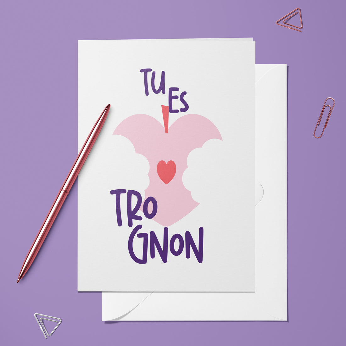 Carte pliée Tu es trognon posée avec un stylo doré et son enveloppe, trognon de pomme en forme de cœur