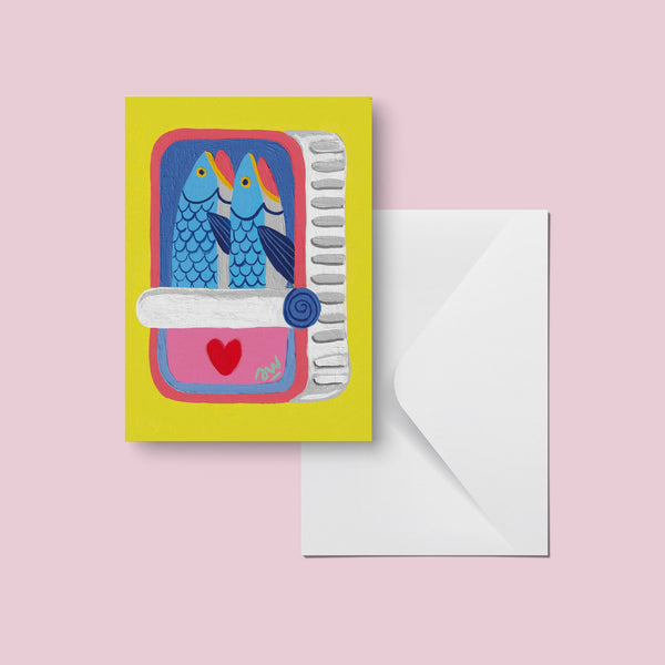 Carte Duo d'Amoureux et son enveloppe sur fond rose, deux sardines bleues dans une boîte au cœur rouge
