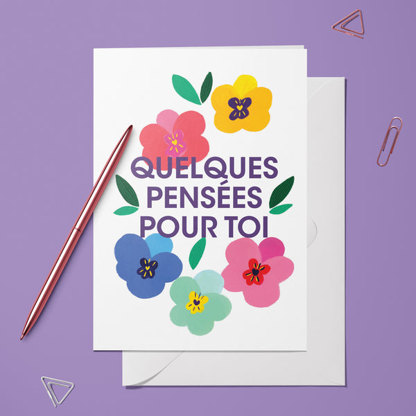 Carte pliée Pensées pour toi posée avec un stylo doré et son enveloppe, message entouré de fleurs colorées
