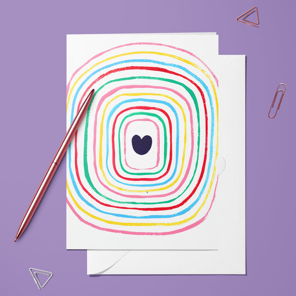 Carte pliée Cœur Spirale posée avec un stylo doré et son enveloppe, spirale colorée autour d'un cœur bleu nuit