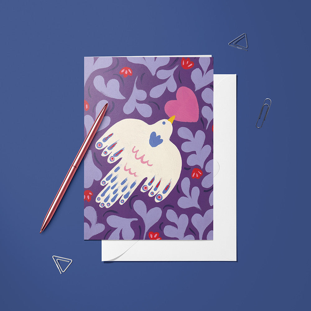 Carte Oiseaux Cœur posée avec un stylo doré et son enveloppe sur fond bleu nuit