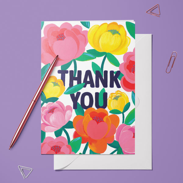 Carte pliée Thank you Éclat de Pivoine posée avec un stylo doré et son enveloppe, message entouré de pivoines
