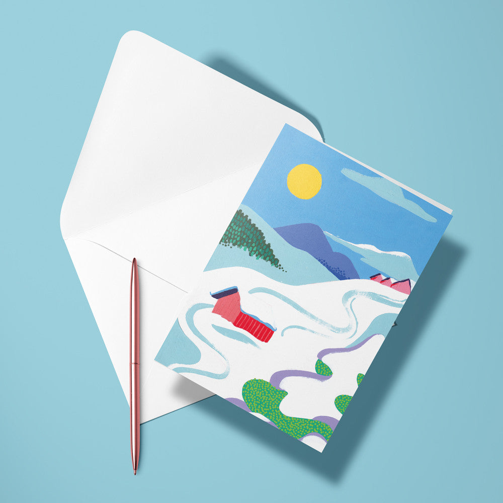 Carte pliée La montagne de Stéphanie posée avec un stylo doré et son enveloppe, paysage de montagne enneigée