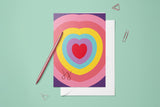 Carte Cœur Arc-en-ciel du pack thème Amour 3, posée avec un stylo doré et son enveloppe