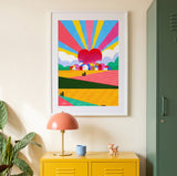 Tirage d'art Campagne mon amour encadré de blanc au-dessus d'un meuble jaune, entre une lampe rose et une plante verte