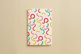 Carnet du pack Danse des courbes, couverture crème parsemée de courbes colorées
