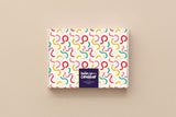 Coffret papeterie Party fermé, boîte crème parsemée de courbes colorées signée Hello couleur