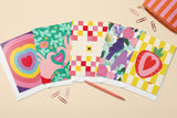 Pack 5 cartes pliées thème Amour 2 étalé en éventail avec un crayon et des trombones