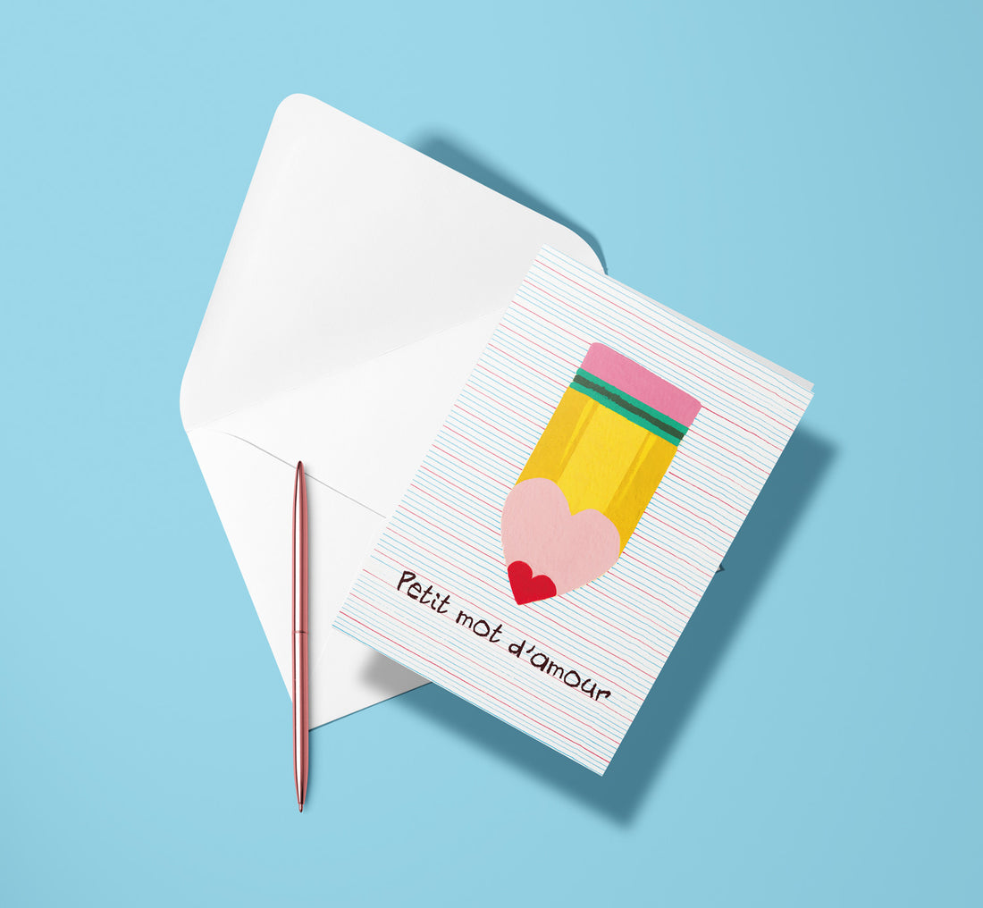 Carte pliée Petit mot d'amour posée avec un stylo doré et son enveloppe, crayon posé sur une page lignée