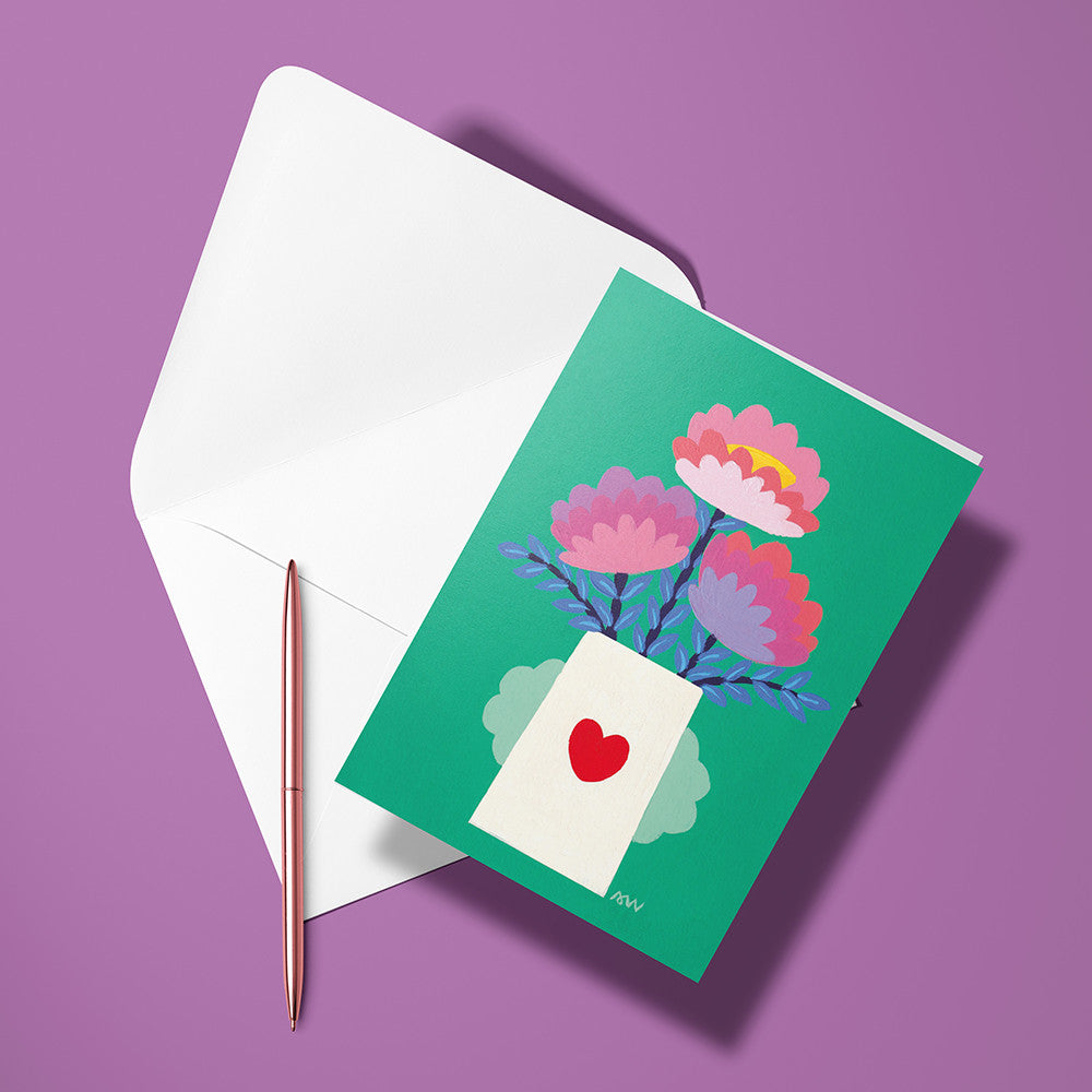 Carte pliée Vase avec Cœur posée avec un stylo doré et son enveloppe, fleurs roses dans un vase orné d'un cœur