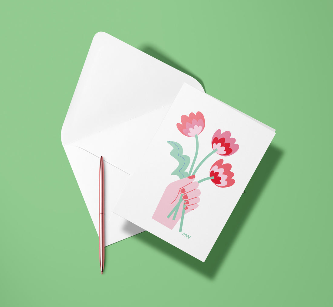 Carte pliée Bouquet de Fleurs posée avec un stylo doré et son enveloppe sur un fond vert