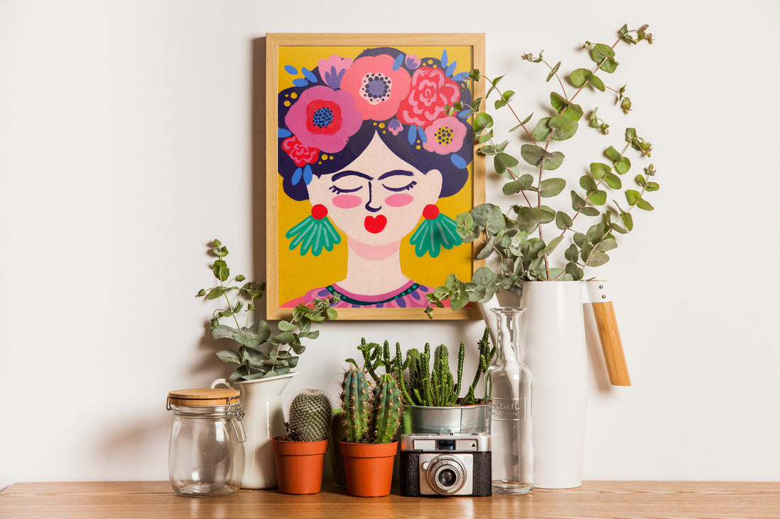 Carnet du petit pack Signature Frida posé sur une étagère, parmi des cactus et un appareil photo vintage