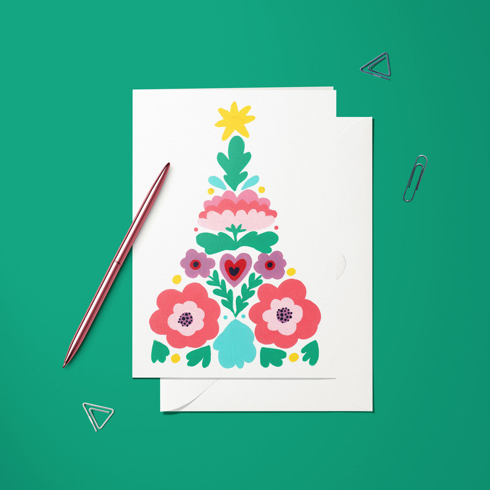 Carte pliée Sapin Scandinave posée avec un stylo doré et son enveloppe, sapin composé de fleurs stylisées