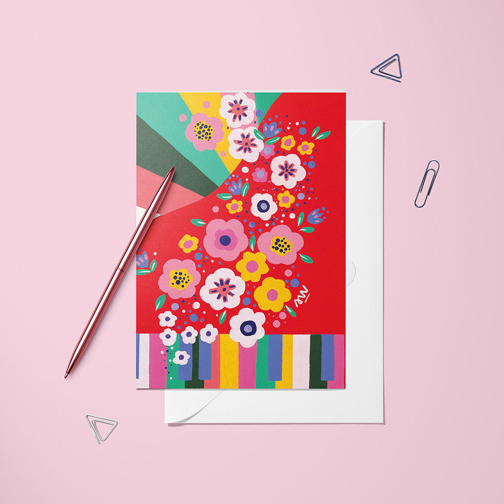 Carte pliée Piano Fleuri posée avec un stylo doré et son enveloppe, piano rouge couvert de fleurs